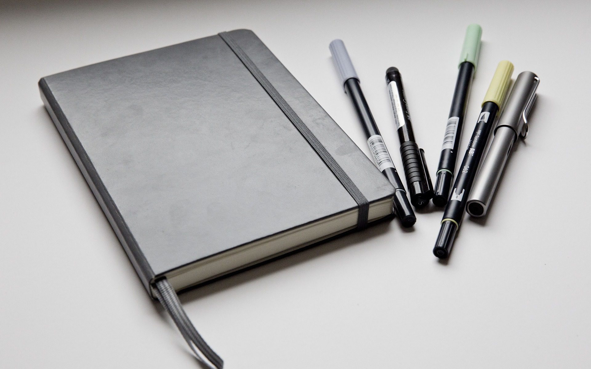 A notebook and some pens on top of the table.