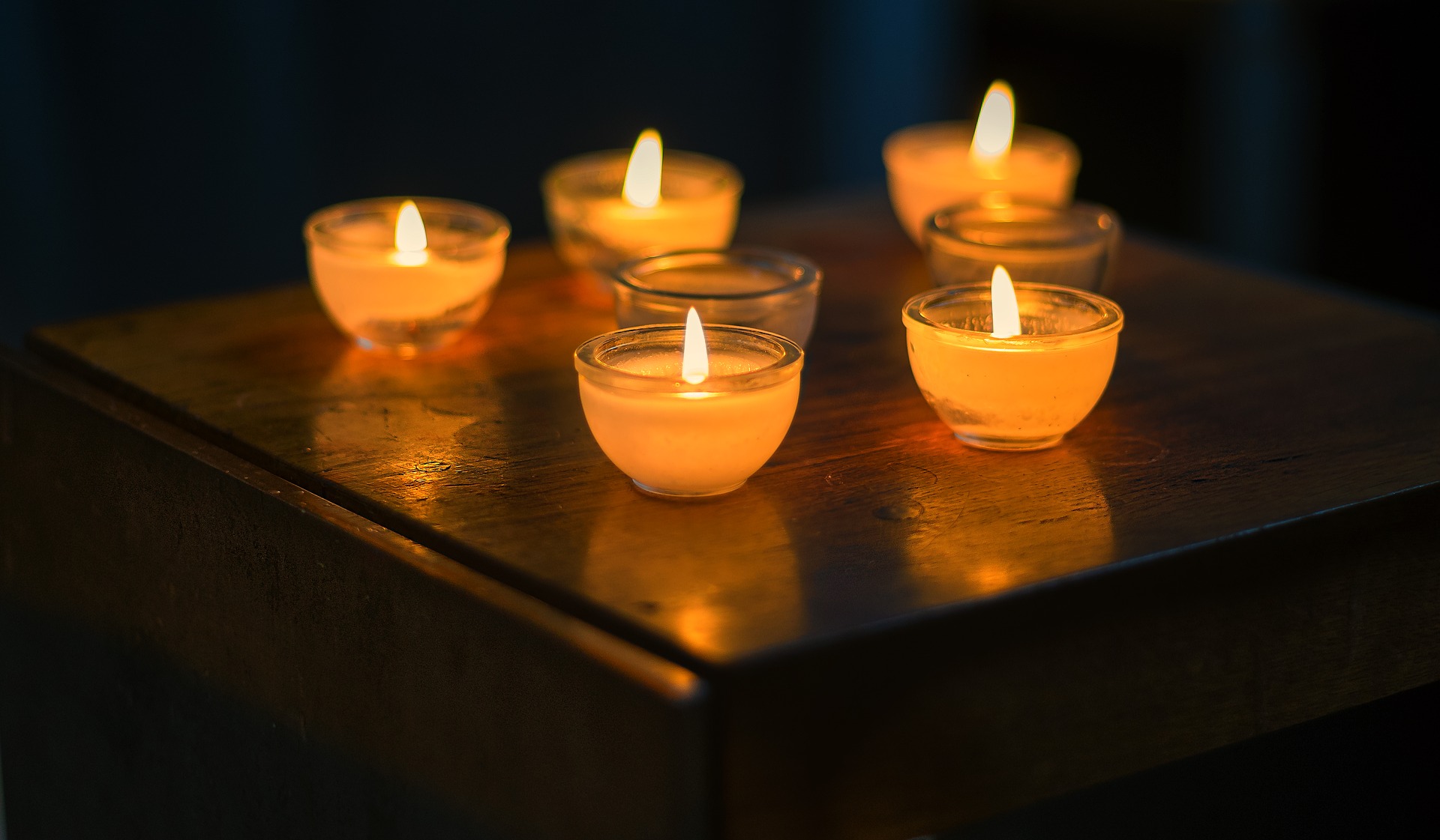 A group of candles lit on top of a wooden table.