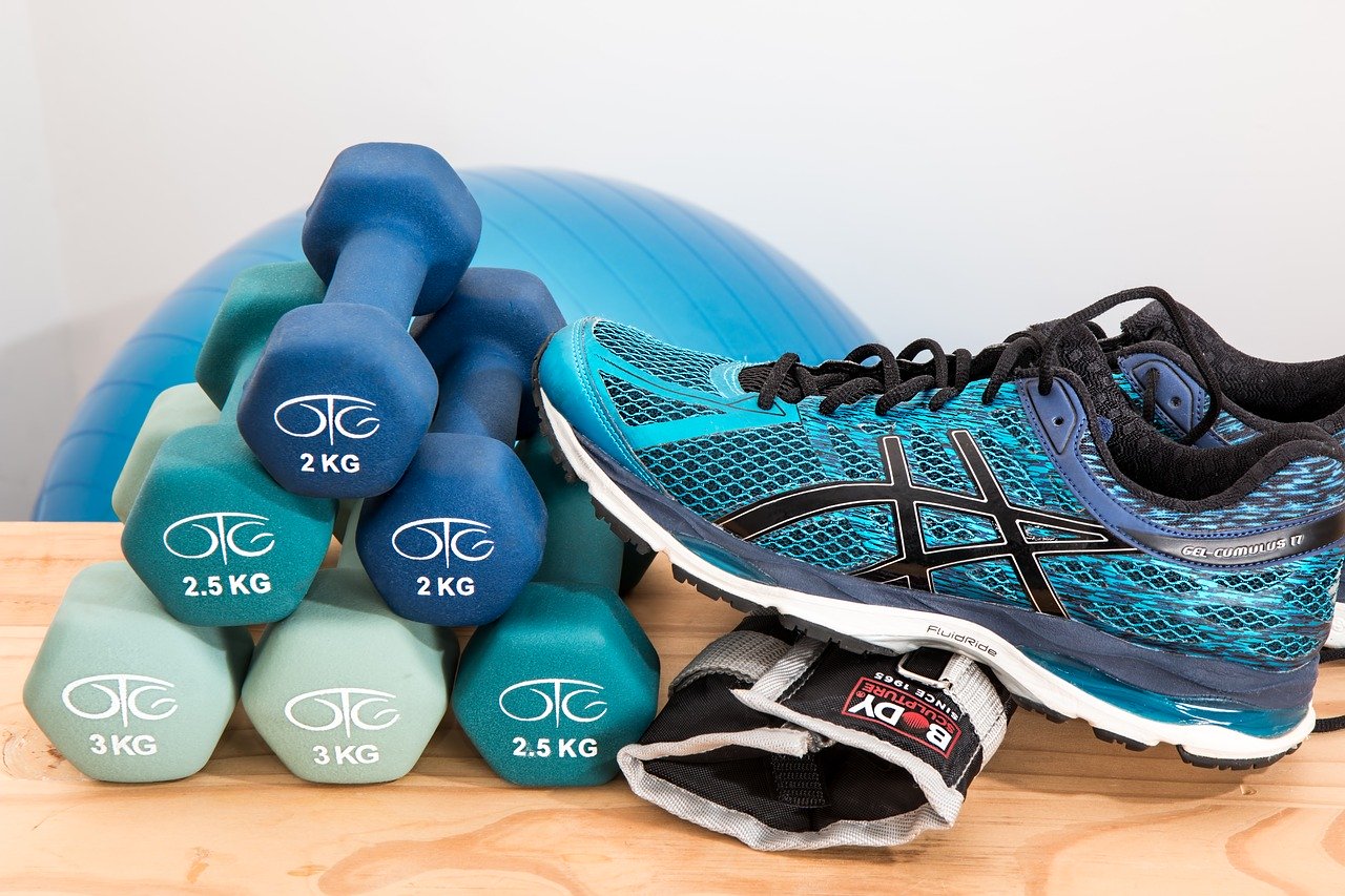 A pair of blue dumbbells sitting next to a shoe.