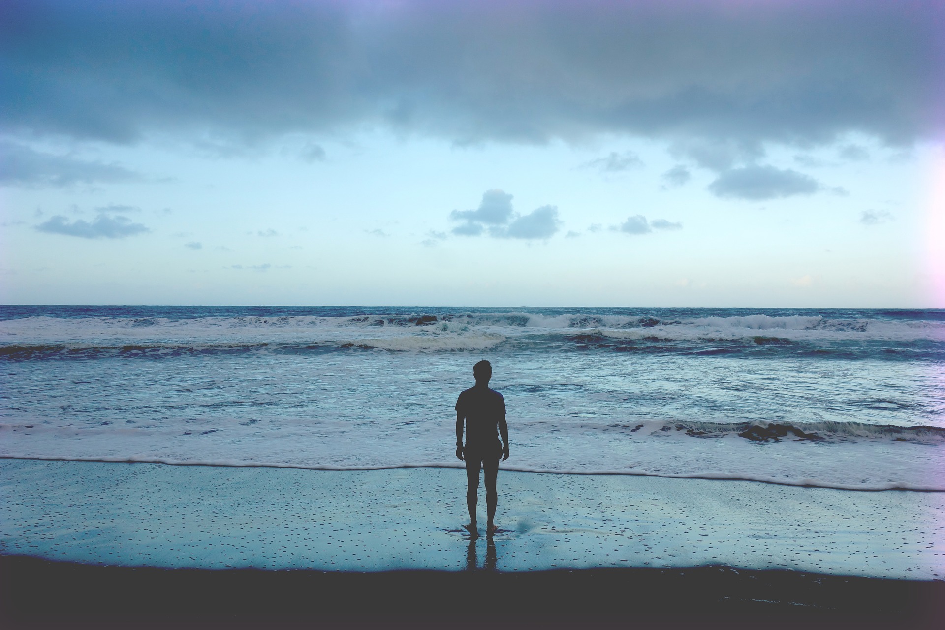 A person standing on the beach looking out at the ocean.