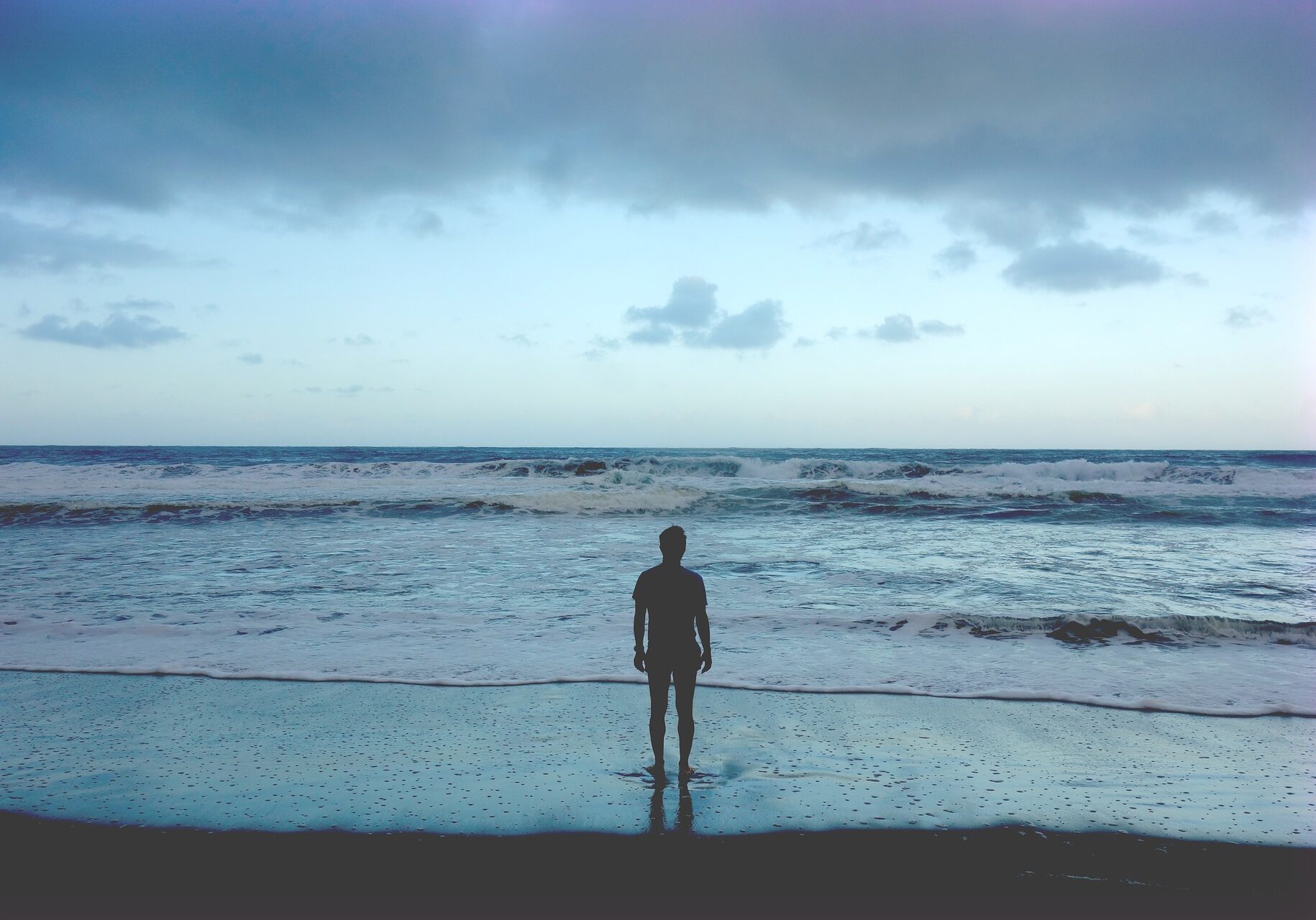 A person standing on the beach looking out at the ocean.
